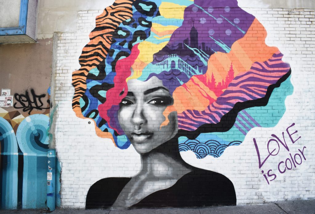 bright graffiti of a beautiful woman with multicolored hair and the slogan love is color