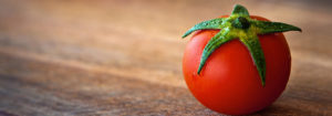 Small tomato on wooden surface.