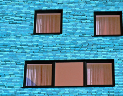 Bright blue brick building with many square windows